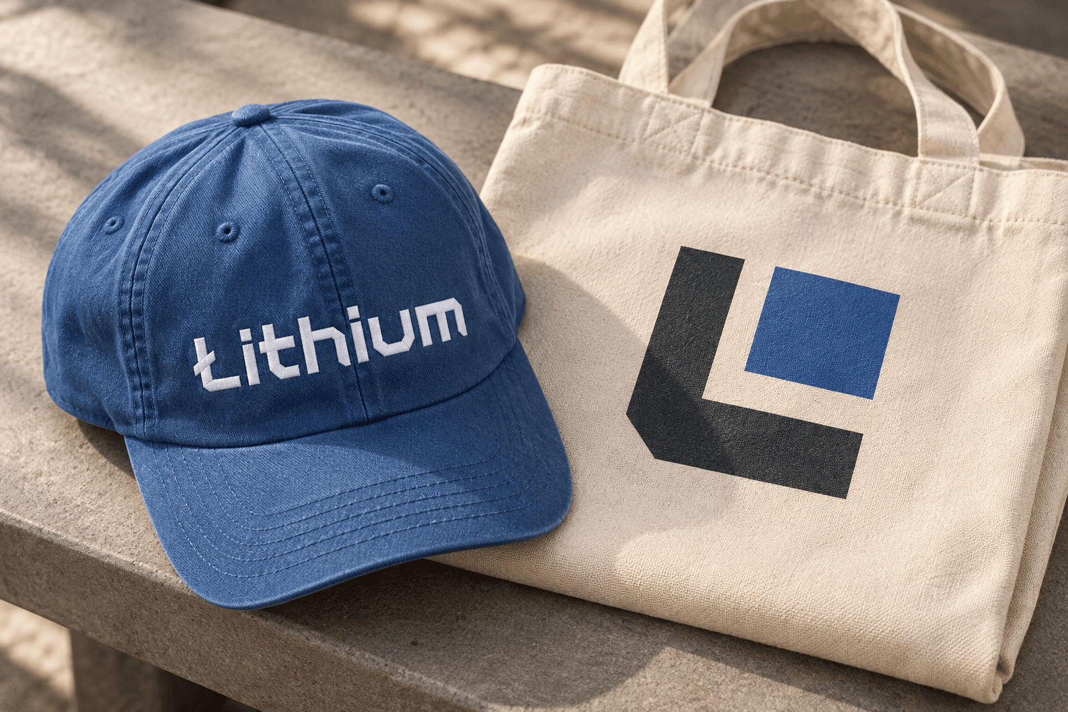 Concept mockup of a blue cap with the Lithium wordmark and a cream canvas tote with the Lithium symbol.